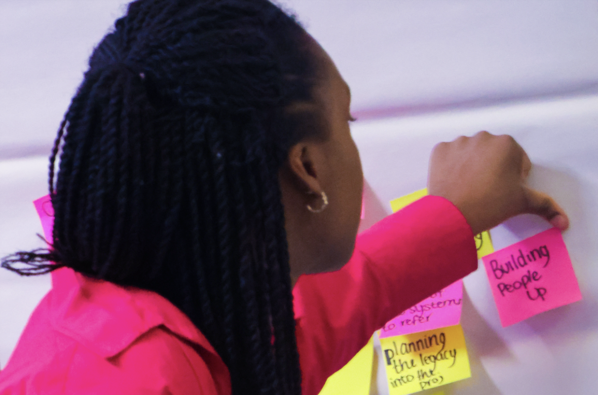 a black woman sticking post it notes to a wall